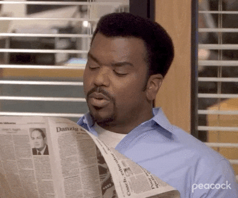 GIF de cena da série The Office com o personagem Darryl lendo um jornal.