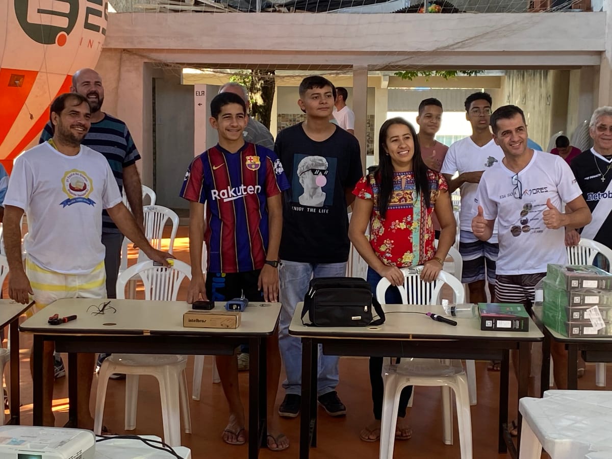 A group of people standing behind a table where boxes of telecommunications equipment are piled up.