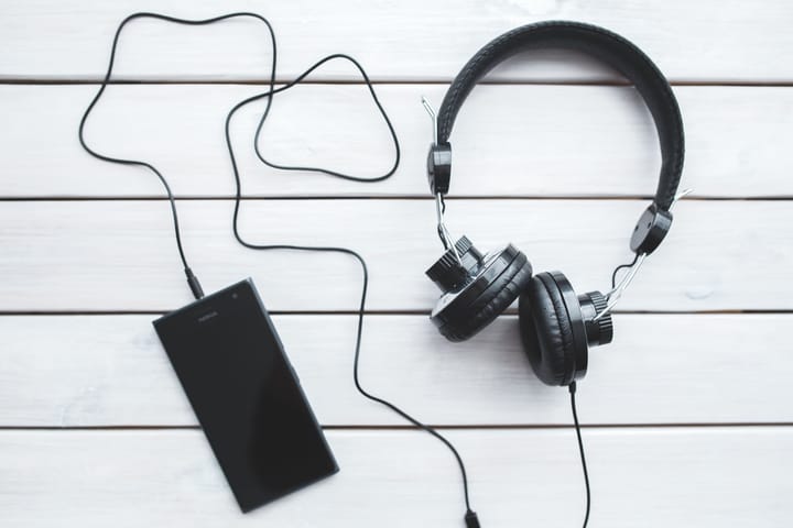 Vista superior de um smartphone preto e um par de fones de ouvido over-ear pretos.